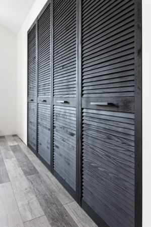 Black wooden wardrobe decorated with blinds, wardrobe with blinds decoration.